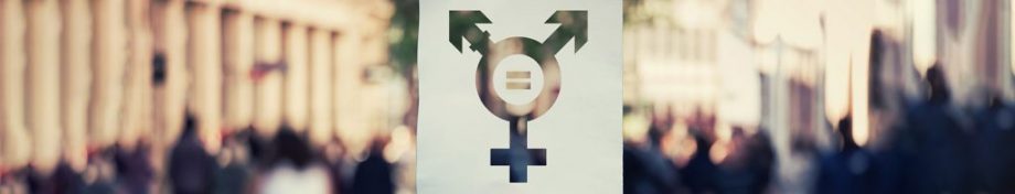 Hand holding a paper sheet with transgender symbol and equal sign inside. Equality between genders concept over a crowded city street background.