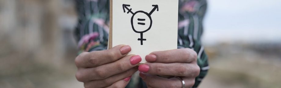 Closeup of hands holding a notepad with a transgender symbol drawn in it.