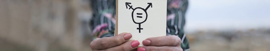Closeup of hands holding a notepad with a transgender symbol drawn in it.