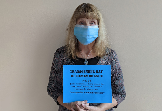 Members of the Center for Transgender Health staff hold signs in solidarity while wearing masks.
